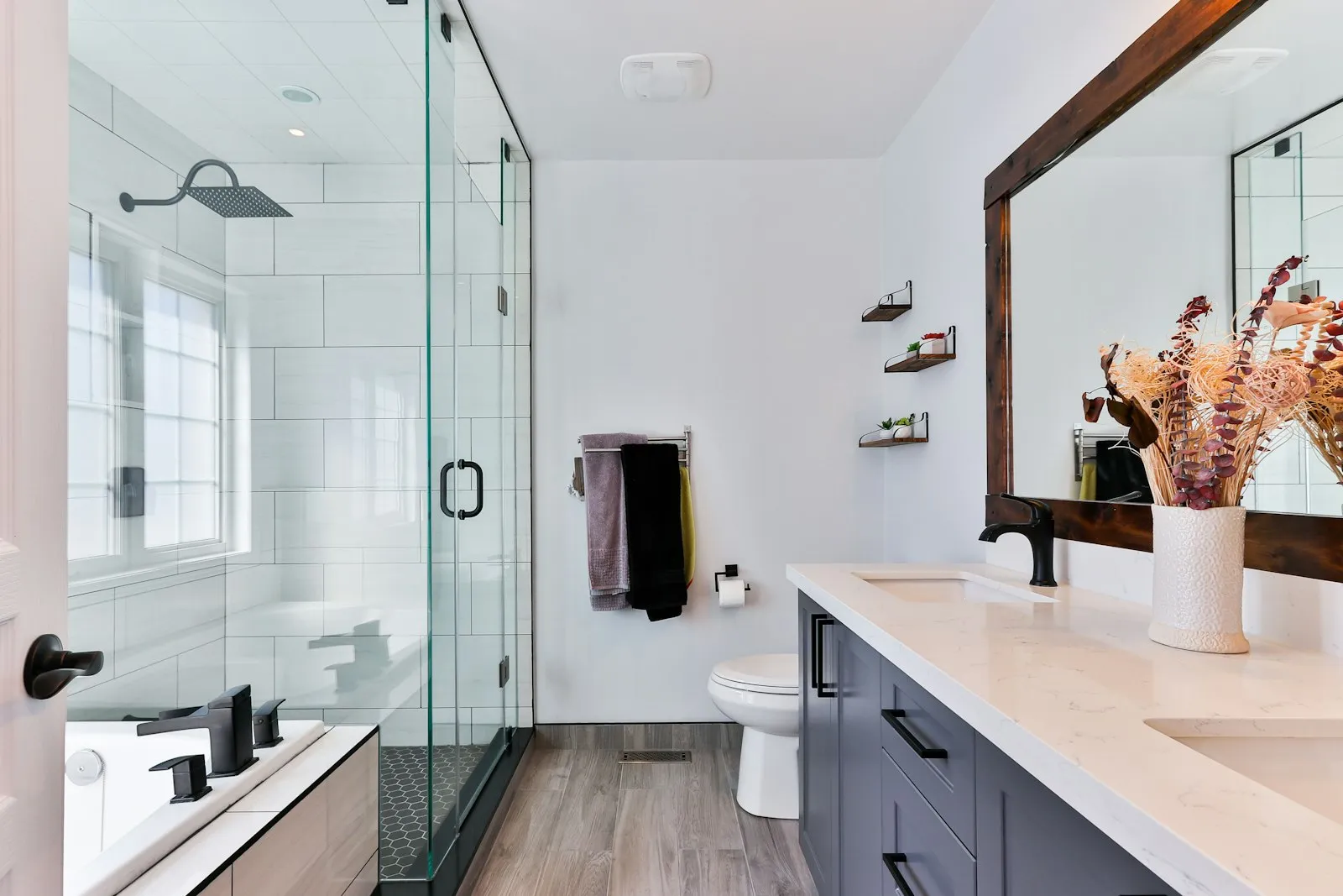 Kamar mandi modern dengan shower kaca, wastafel ganda, dan lantai marmer